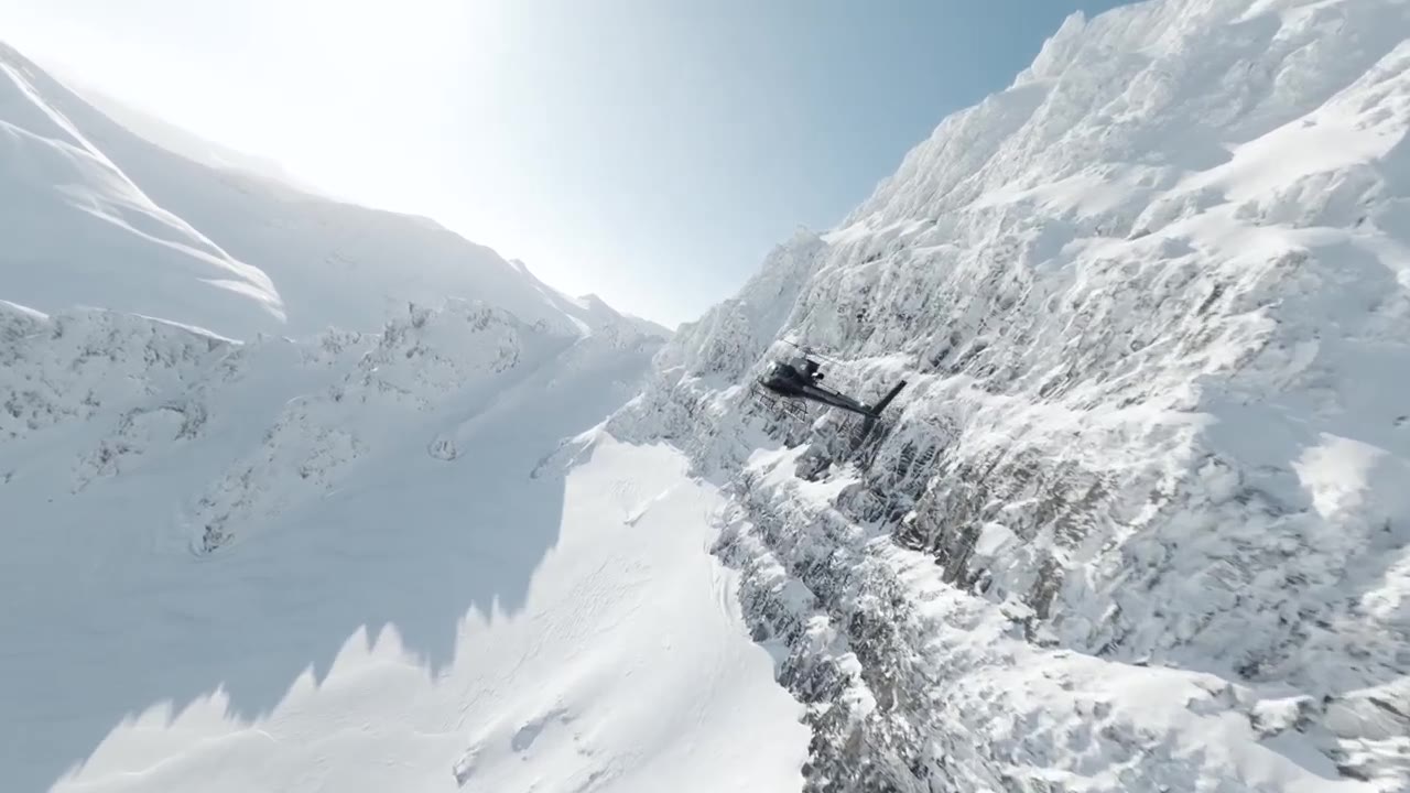 Helicopter flying through a sunlit snow couloir in Iceland